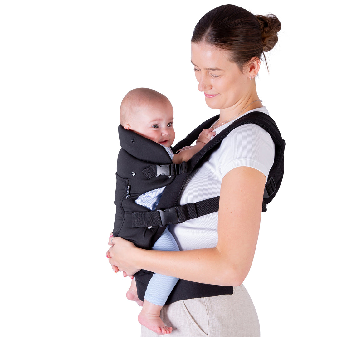 Woman carrying a baby in a black baby carrier against a white background
