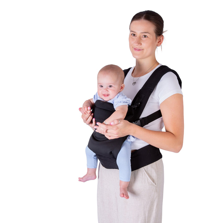 Woman holding a baby in a black baby carrier against a white background