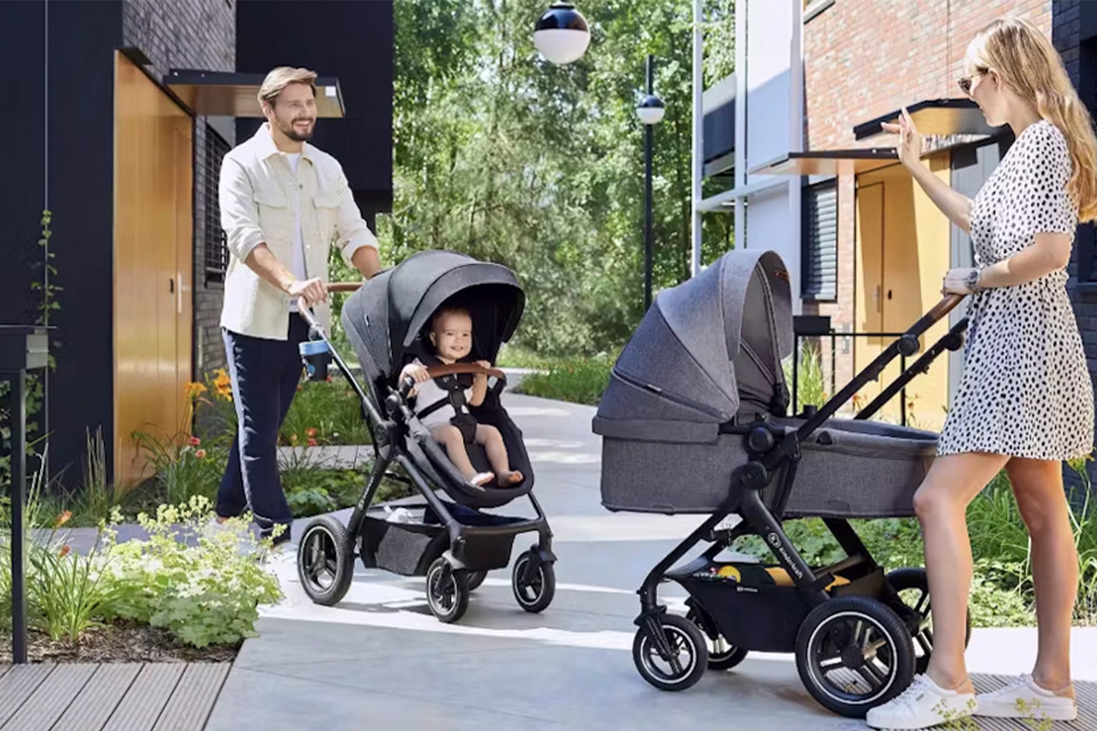 Two people pushing strollers with a child in an urban setting