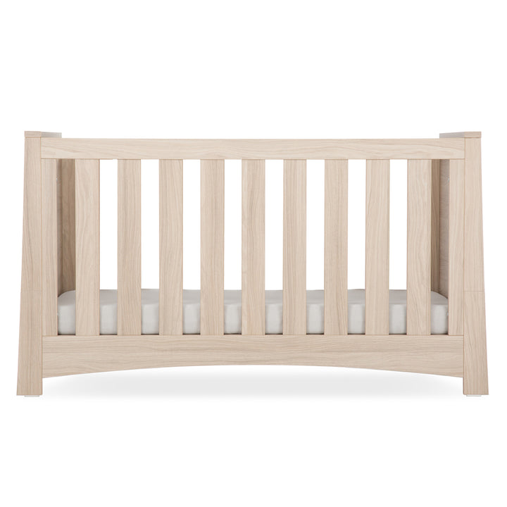Wooden crib with a white mattress on a white background