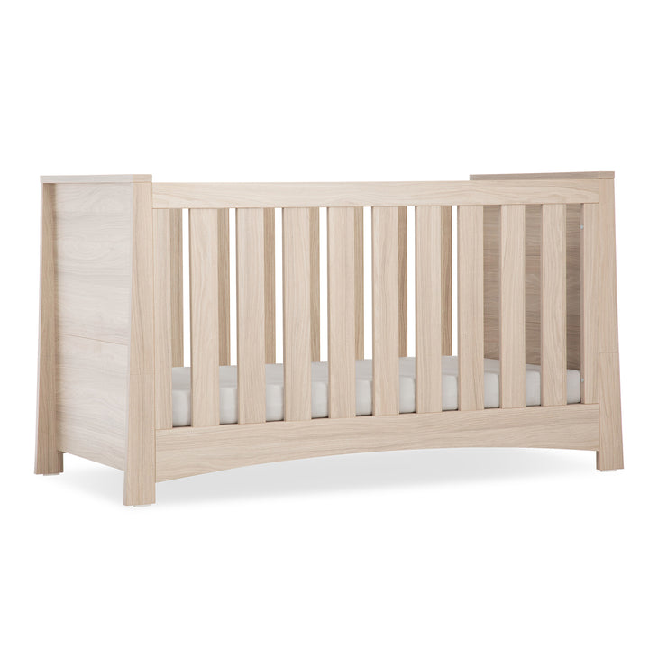 Beige crib with white mattress on a white background