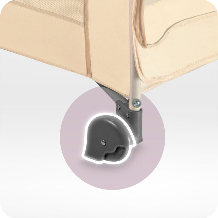 Close-up of a beige travel cot with a focus on a wheel on a light gray background