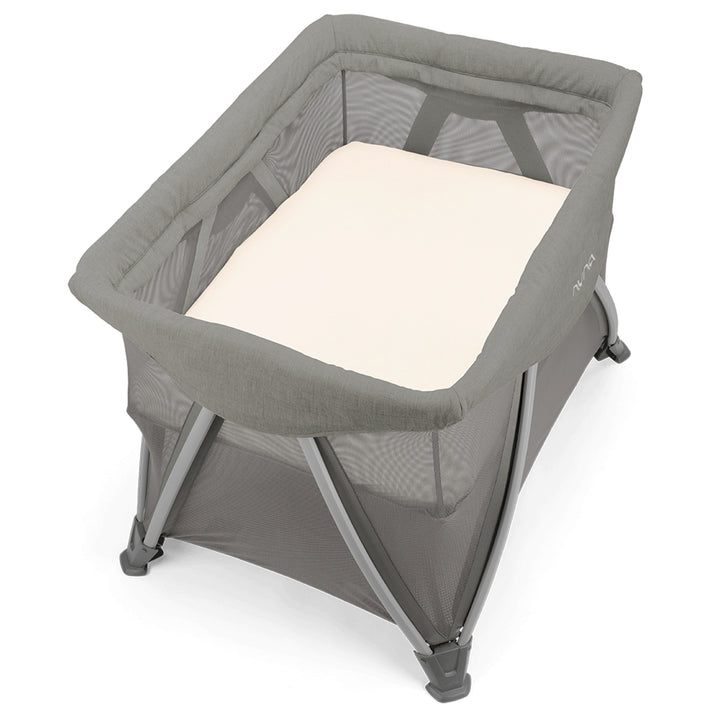 Portable crib with a beige mattress on a white background