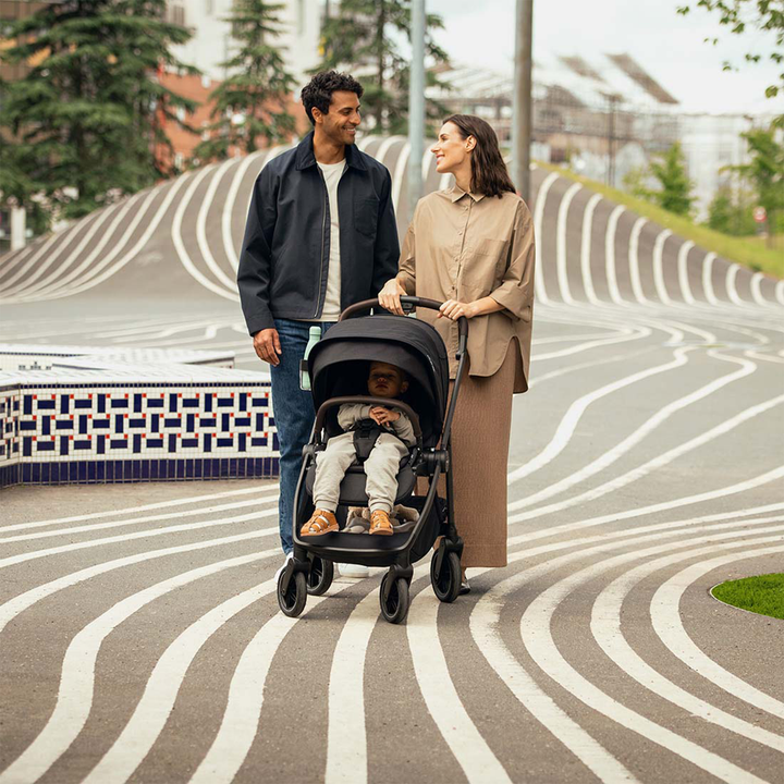 Man and woman pushing a stroller with a child on a wavy pavement.